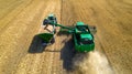 Aerial view of combine harvester unloading grain in cargo trailer working during harvesting season on large ripe wheat field in Royalty Free Stock Photo