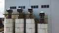 Aerial view of concrete mixing plant and four tanks. Stock footage. Flying over cement storage silos, industrial