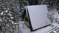 Aerial view of coniferous winter forest and a small glamp house. Clip. Flying above frozen trees and snow covered ground Royalty Free Stock Photo