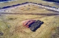 Aerial view of a construction site for the development of a new housing area with the road substructure in the back and mounds of