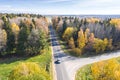 Aerial view of country road surrounded by colorful autumn trees