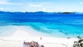 Aerial view of a couple in a pristine sandy in front of paradise blue water. Philippines sea in idyllic coastline.