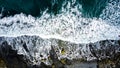 Aerial view on crashing waves with colourful stones on black sand beach.