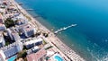 Aerial view of a crowded beach with umbrellas, people swimming in the sea, sunny day. Drone view of beach with white