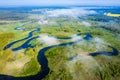 Aerial view on curved river through white clouds. River on green meadow from above. Mist river Royalty Free Stock Photo