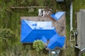 Aerial view of damaged in hurricane Ian house roof covered with blue protective tarp against rain water leaking until Royalty Free Stock Photo