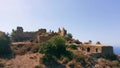 Aerial view of desert rocky small city on the top of mountain hill. In the background coastline with modern city. Aerial