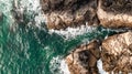 Aerial view directly above waves crashing onto rocky cliffs in Cornwall Royalty Free Stock Photo