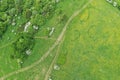 Aerial view of dirt road, group of broadleaf trees and grassland with interesting, round and kidney shaped grass patterns.