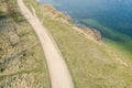 Aerial view of dirt road between lake and meadow at sunny spring day Royalty Free Stock Photo