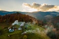 Aerial view of distant village with small shepherd houses on wide hill meadows between autumn forest trees in Ukrainian Carpathian Royalty Free Stock Photo