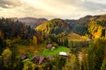 Aerial view of distant village with small shepherd houses on wide hill meadows between autumn forest trees in Ukrainian Carpathian Royalty Free Stock Photo