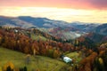 Aerial view of distant village with small shepherd houses on wide hill meadows between autumn forest trees in Ukrainian Carpathian Royalty Free Stock Photo