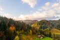 Aerial view of distant village with small shepherd houses on wide hill meadows between autumn forest trees in Ukrainian Carpathian Royalty Free Stock Photo
