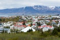 Aerial view of downtown rooftops seen during a grey cloudy day with sea and mountains in the background