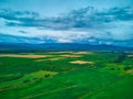 Aerial view from drone flight over different agricultural fields and mountains behind with clouds