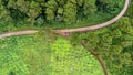 Aerial view from drone of mountain road with sun shining in forest. Top view of a road on a hill in a beautiful lush green forest Royalty Free Stock Photo