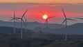 Aerial view drone orbit around silhouette wind turbines farm at sunset