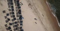 Aerial view, drone shot on the coast of Angola, people resting and playing on beach sand, surf boards on thatched huts