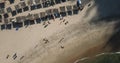 Aerial view, drone shot on the coast of Angola, people resting and playing on beach sand, surf boards on thatched huts Royalty Free Stock Photo