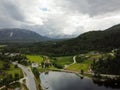 Aerial view, drone shot of Norwegian fjord mountains with green pines and private houses and highway next to them Royalty Free Stock Photo