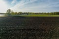 Aerial view with a drone of a spring wavy agricultural countryside landscape with plowed and unplowed fields and trees