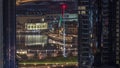 Aerial view of Dubai Fountain in downtown with palms in park next to shopping mall and souq night to day timelapse, UAE