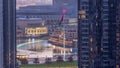 Aerial view of Dubai Fountain in downtown with palms in park next to shopping mall and souq night to day timelapse, UAE