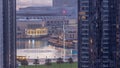 Aerial view of Dubai Fountain in downtown with palms in park next to shopping mall and souq night to day timelapse, UAE