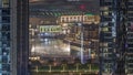 Aerial view of Dubai Fountain in downtown with palms in park next to shopping mall and souq night timelapse, UAE