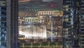 Aerial view of Dubai Fountain in downtown with palms in park next to shopping mall and souq night timelapse, UAE