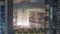 Aerial view of Dubai Fountain in downtown with palms in park next to shopping mall and souq night timelapse, UAE