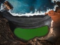 Aerial view of the El lago Verde Lanzarote - green lagoon with blue ocean - top view. Blue Atlantic ocean with waves and black