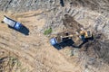 Aerial view of excavator and dump trucks working at the construction site Royalty Free Stock Photo