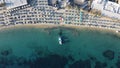 Aerial view of exotic Ornos beach, with lots of umbrellas and a moored boat.