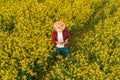 Aerial view of farmer using drone remote controller in blooming rapeseed field