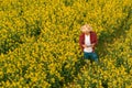 Aerial view of farmer using drone remote controller in blooming rapeseed field