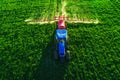 Aerial view of farming tractor plowing and spraying on field