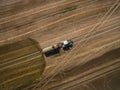 Aerial view of a farming tractor with a trailer fertilizes a freshly plowed agriculural field with manure