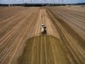 Aerial view of a farming tractor with a trailer fertilizes a freshly plowed agriculural field with manure