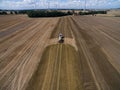 Aerial view of a farming tractor with a trailer fertilizes a freshly plowed agriculural field with manure