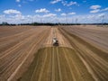Aerial view of a farming tractor with a trailer fertilizes a freshly plowed agriculural field with manure