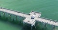 An aerial view of a fishing pier in Panama City Beach,Florida in the waters of the emerald green Gulf of Mexico