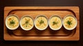 Aerial View Of Five Small Bowls Of Cheese Soup On Wooden Tray