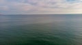 An aerial view of a flat sea water with some white cliff in the background under a cloudy white sky Royalty Free Stock Photo