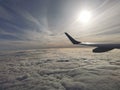 Aerial view of fluffy clouds with the sun under the wing of the plane Royalty Free Stock Photo