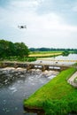 An aerial view with a flying drone in the background above a weir in the river Vecht. Lock keepers house next to the Royalty Free Stock Photo