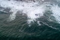 aerial view of the foamy waves against the rocks of the coastline