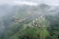 Aerial view of foggy mountain and hut resort on hillside in tropical rainforest on rainy day