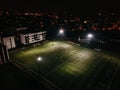 Aerial view of football pitch at night with amateur football players playing the game in the city